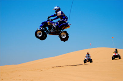 People riding ATV's on a sand dune.